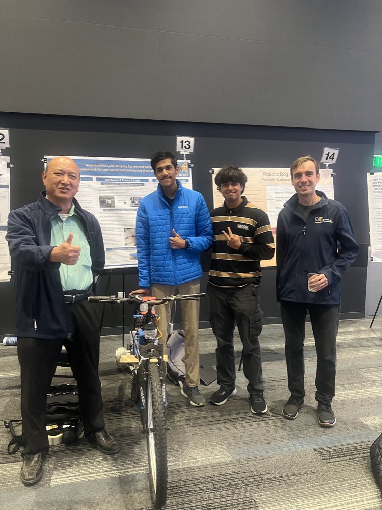 Four people standing with the autonomous bicycle at a University of California, Merced poster presentation